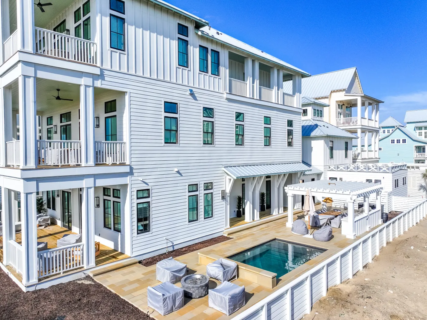 Pool and furnished terrace behind a three-story beach house