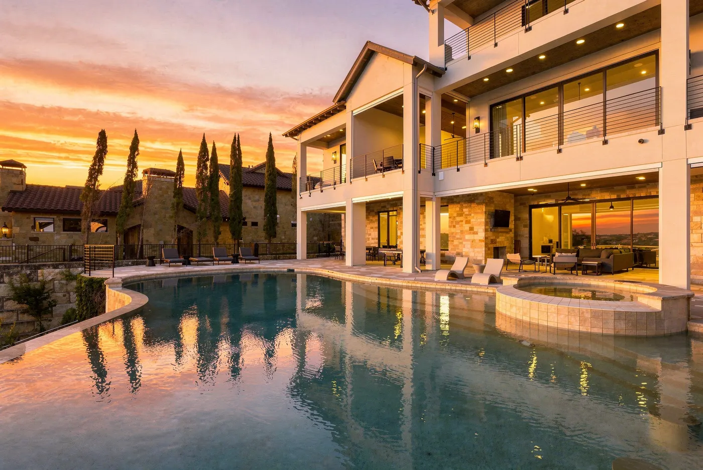 An infinity-edge pool and lit terraces at sunset above Lake Travis