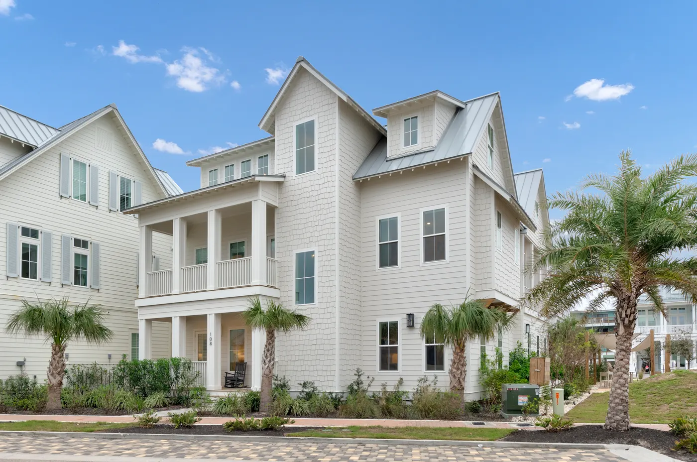A bright coastal home behind palm trees
