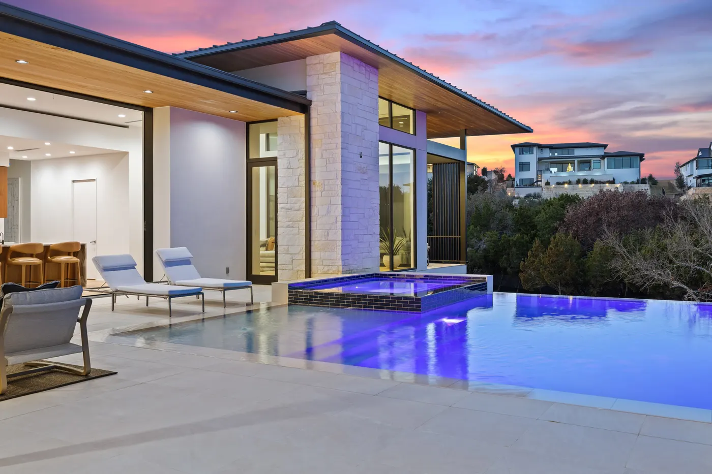 Glass pavilion and pool at dusk under a pink sky